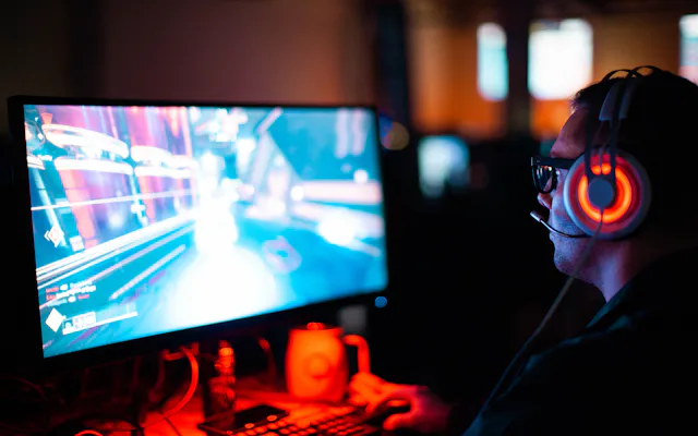 Player wearing a headset watching a live-streamed game on a glowing monitor